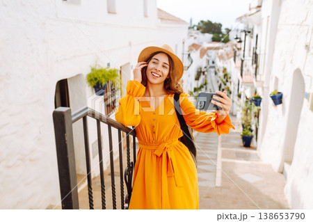Young woman to take a quick selfie as a souvenir of her trip in a sunny village. Tourist Adventure 138653790