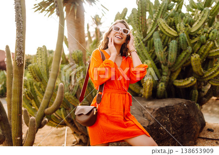 Stylish trendy woman tourist posing against cactuses. Outdoor summer portrait. Positive emotions. Stylish trendy woman tourist posing against cactuses. Outdoor summer portrait. Positive emotions. 138653909