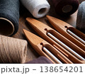 Elegant composition of wooden boat shuttles and spools of weaving yarn on a dark wooden table. Traditional textile tools and the craftsmanship of hand weaving 138654201
