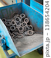 Collection of metal gears and sprockets stored in a blue industrial bin at a tractor manufacturing plant 138654204