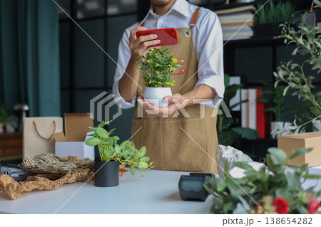 A shop owner or employee using phone checking order or to document the plant for inventory. 138654282