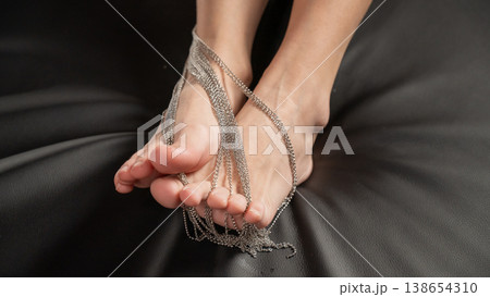 Foot fetish. Close-ups of naked female feet with silver chain jewelry. 138654310