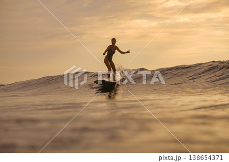 Golden Hour Female Surfer Maintains Steady Stance On Surfboard Golden Hour Female Surfer Maintains Steady Stance On Surfboard 138654371