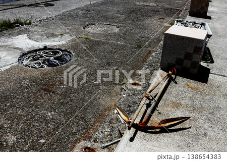 漁港の岸壁に放置された古い錆びた碇と漁網のロープ 138654383