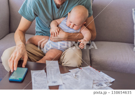 Father sitting on sofa holding baby while calculating monthly expenses with receipts at home. Stressed dad managing budget and childcare. Financial stress, parenthood and real life concept Father sitting on sofa holding baby while calculating monthly expenses with receipts at home. Stressed dad managing budget and childcare. Financial stress, parenthood and real life concept 138654635