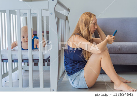 Very tired mother sitting by baby crib at home feeling exhausted. Sleep deprived mom caring for newborn at night. Parenting fatigue, motherhood stress, childcare and real family life concept 138654642