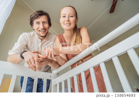 Parents looking into baby crib from infant point of view. Mother and father smiling down at newborn with love and care. Family bonding, parenthood, childhood memory and emotional connection concept Parents looking into baby crib from infant point of view. Mother and father smiling down at newborn with love and care. Family bonding, parenthood, childhood memory and emotional connection concept 138654693