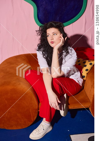 Woman in casual attire enjoys tranquil moment on vibrant furniture 138654998