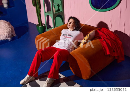 Serene female figure seated on vibrant sectional during evening ambiance Serene female figure seated on vibrant sectional during evening ambiance 138655051
