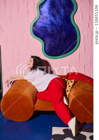 Woman smiling brightly while seated on vibrant living room furniture Woman smiling brightly while seated on vibrant living room furniture 138655106
