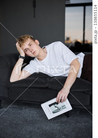 Young Caucasian man lounging with magazine in loft setting Young Caucasian man lounging with magazine in loft setting 138655114