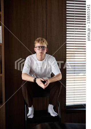 Confident Caucasian man seated confidently in warm modern space Confident Caucasian man seated confidently in warm modern space 138655141