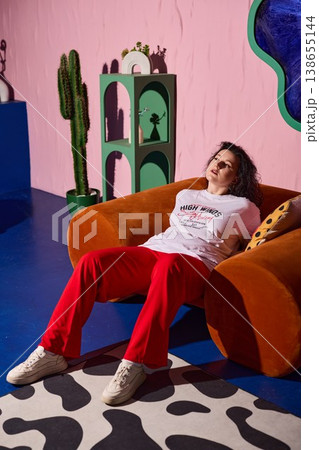 Chilled lady reclining on colorful sofa with cactus shadow mood Chilled lady reclining on colorful sofa with cactus shadow mood 138655144