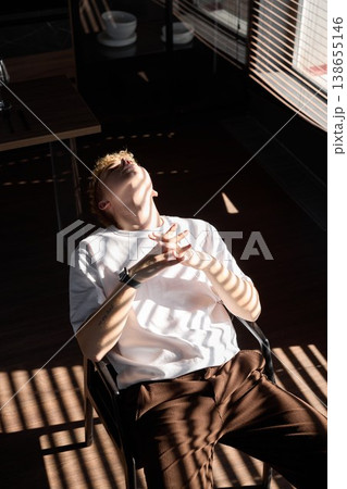 Young man quietly writes while sunlight filters through blinds Young man quietly writes while sunlight filters through blinds 138655146