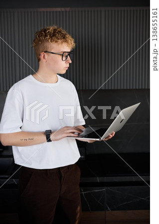 Teenager with glasses examines messages in office environment 138655161