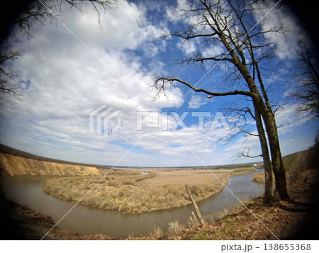 The Don River flows in a curved path across the land. Trees stand nearby as vast clouds fill the sky. This scene shows nature on a clear day. 138655368