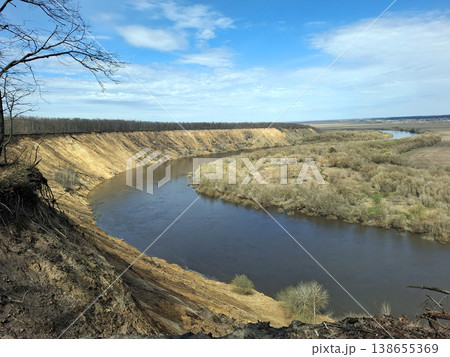 The Don River flows through a valley surrounded by steep sandy cliffs. Early spring vegetation appears along the riverbank. The sky is bright and blue. The Don River flows through a valley surrounded by steep sandy cliffs. Early spring vegetation appears along the riverbank. The sky is bright and blue. 138655369