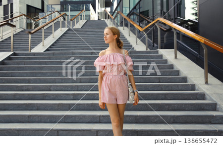 Beautiful modern young woman on the stairs on city street in summer dress Beautiful modern young woman on the stairs on city street in summer dress 138655472