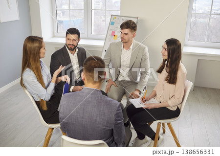 Group of young business professionals sitting in circle and sharing ideas during office team meeting 138656331