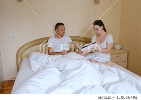 Father and teenage daughter studying together at home cozy family moments bedroom weekend learning tablet interaction beige calm interior 138656492