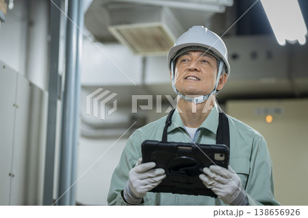 タブレットを持った60代の作業員　ビルメンテナンススタッフ　イメージ　 138656926