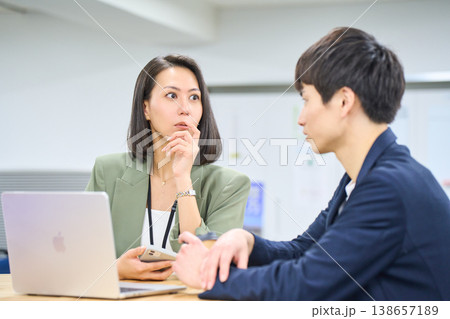 外資系企業で働く日本人ビジネスウーマンが男性同僚に相談するオープンオフィス風景 138657189