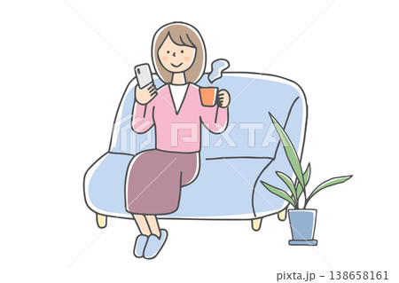 ソファで温かい飲み物を飲みながらスマホを見る女性 138658161