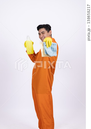 Happy maintenance worker in orange jumpsuit holding a spray bottle 138658217