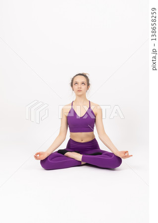 Woman sitting in lotus position and meditating on a mat Woman sitting in lotus position and meditating on a mat 138658259
