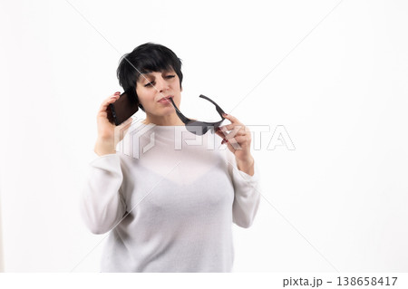 Woman with short hair holding glasses and looking thoughtful 138658417