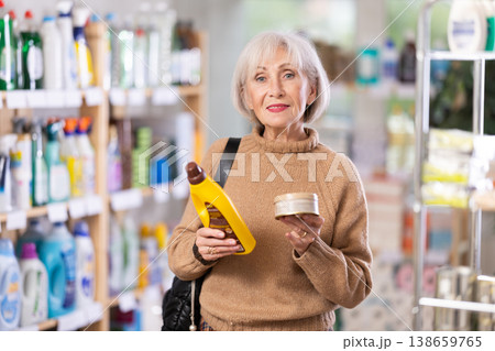 Elderly housewife buys a cleaning product for washing parquet and laminate floors in supermarket Elderly housewife buys a cleaning product for washing parquet and laminate floors in supermarket 138659765