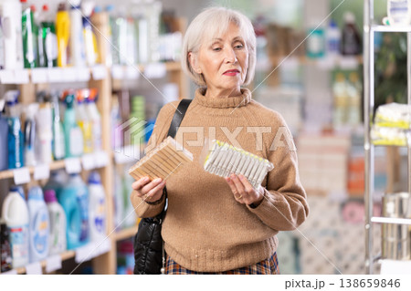 Elderly woman chooses clothespins - wooden or plastic, in hardware store Elderly woman chooses clothespins - wooden or plastic, in hardware store 138659846