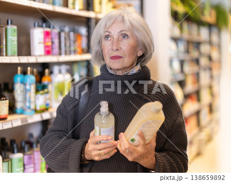 Senior woman reads label, choose and compare shampoo Senior woman reads label, choose and compare shampoo 138659892
