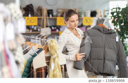 Young woman chooses sweater in clothing store Young woman chooses sweater in clothing store 138659906