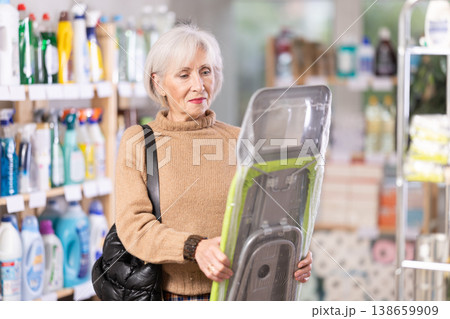 Elderly woman buys convenient lightweight ironing board at hardware store Elderly woman buys convenient lightweight ironing board at hardware store 138659909