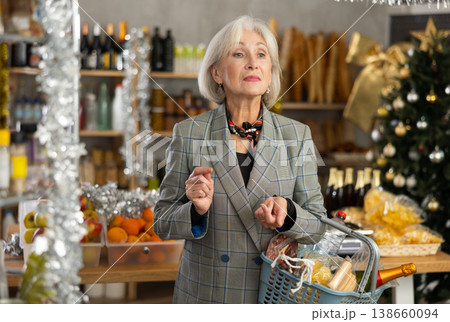Elderly woman with basket of groceries in store 138660094