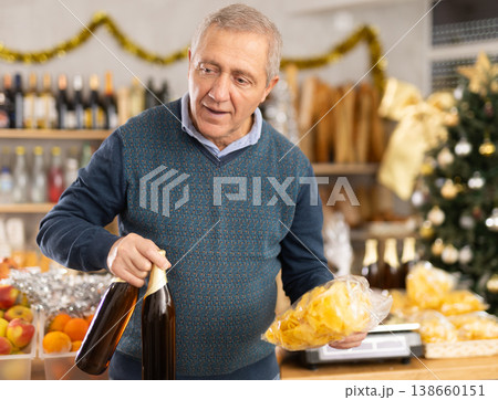 Elderly man chooses beer and chips at grocery store 138660151