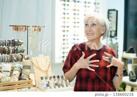 Delighted elderly lady admiring costume jewelry in trendy store Delighted elderly lady admiring costume jewelry in trendy store 138660238