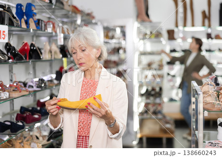 Elderly woman chooses ballet flats in shoe store Elderly woman chooses ballet flats in shoe store 138660243