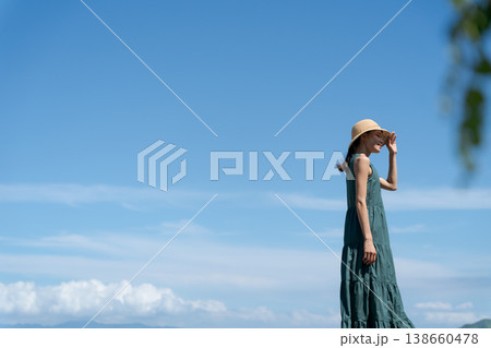 青空の下に立つワンピースの女性 138660478