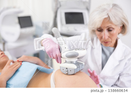 Old woman specialist doing LPG massage of hips of young woman 138660634