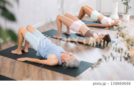 Mom, grandma and teen daughter do half bridge Setu Bandha Sarvangasana, glute bridge pose 138660698