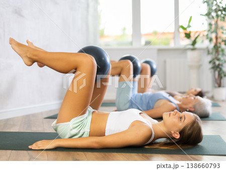 Family grandmother, mother and granddaughter perform fitness exercises lying on floor with softball. 138660793