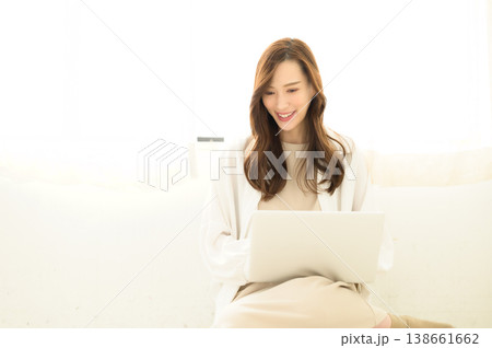 ノートパソコンを膝上に置いて使う女性 138661662