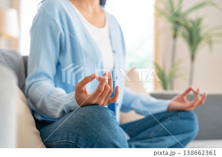 Happy young Asian woman practicing yoga and meditation at home sitting on couch 138662361