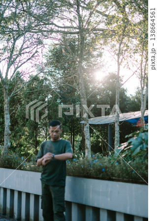 Southeast Asian Man Checking Wristwatch While Standing on Bridge 138664561