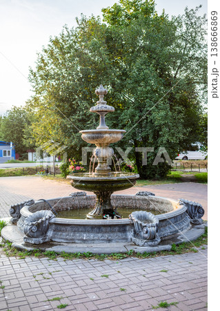 Ornate stone fountain surrounded by greenery in urban park setting Ornate stone fountain surrounded by greenery in urban park setting 138666869