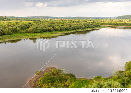 Wide river with banks with lush vegetation, waterlogged blanks and calm water reflections Wide river with banks with lush vegetation, waterlogged blanks and calm water reflections 138666902