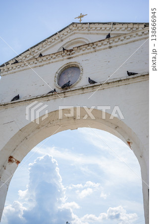 Architectural archway temple gate with pigeons perched under cloudy sky 138666945