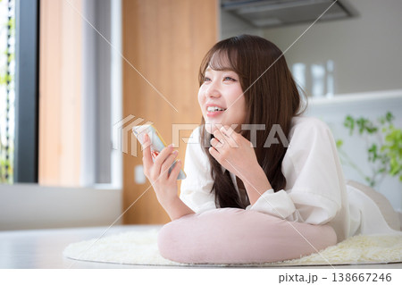 自宅でうつ伏せで寝転がるくつろぎながらスマートフォンを見る女性のリラックス 自宅でうつ伏せで寝転がるくつろぎながらスマートフォンを見る女性のリラックス 138667246